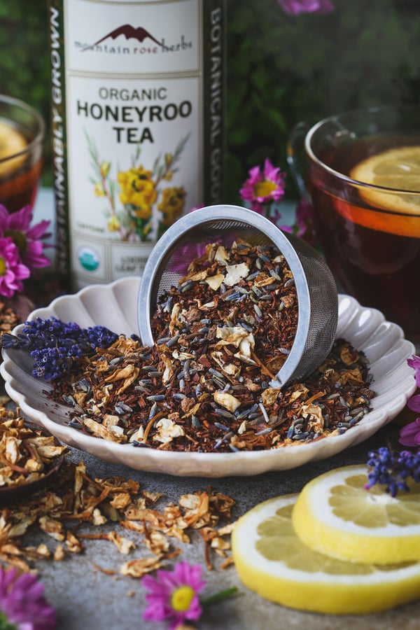 A close up photo featuring jasmine lavender lemonade tea blend in a dish with an infuser basket