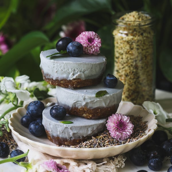 A stack of three lavender cheesecakes topped with blueberries