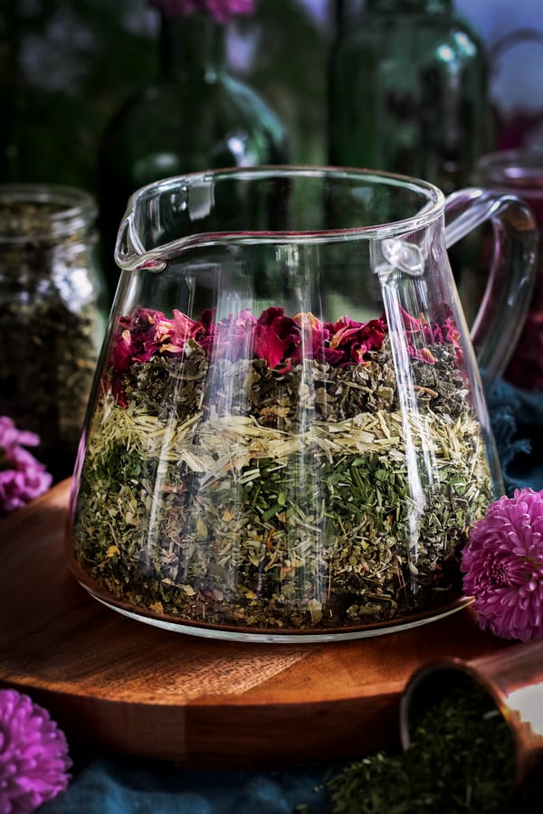 Layers of meditation tea herbs sit in a glass vessel