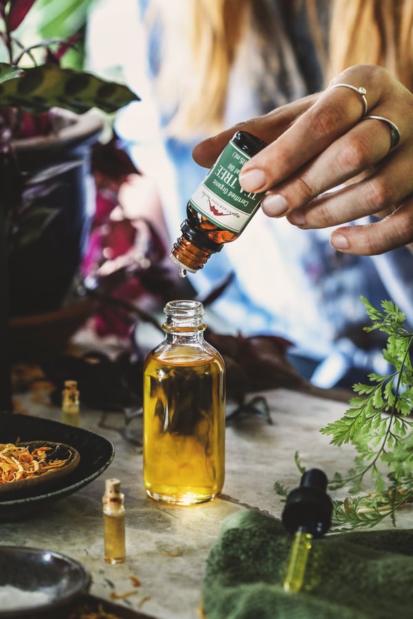 Tea tree essential oil is being dropped into a carrier oil
