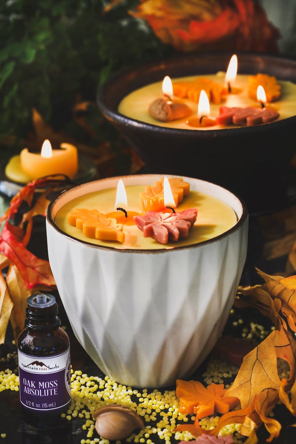 Two handmade candles in repurposed bowls with fall decorations on top