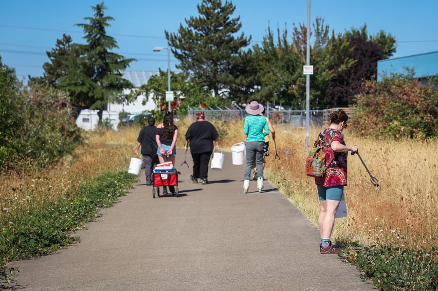 Mountain Rose Herbs employees walk along bike path collecting garbage into buckets