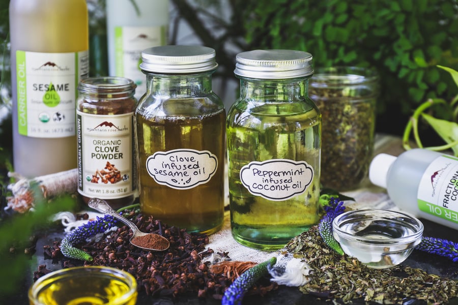Two jars of infused oils for pulling sit beside ingredients