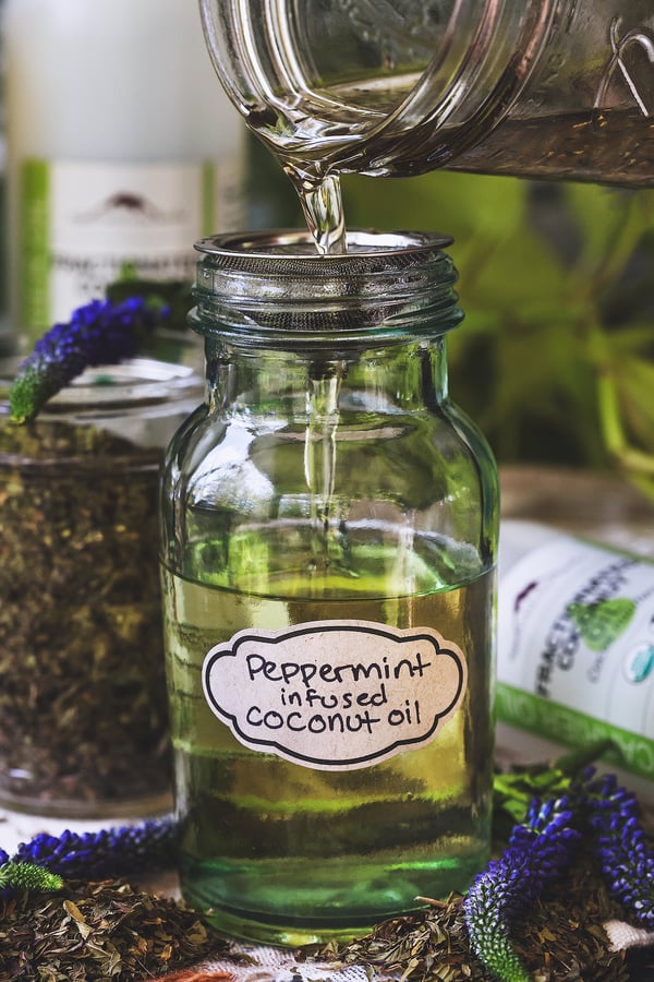 Peppermint infused oil is strained into glass jar for storage