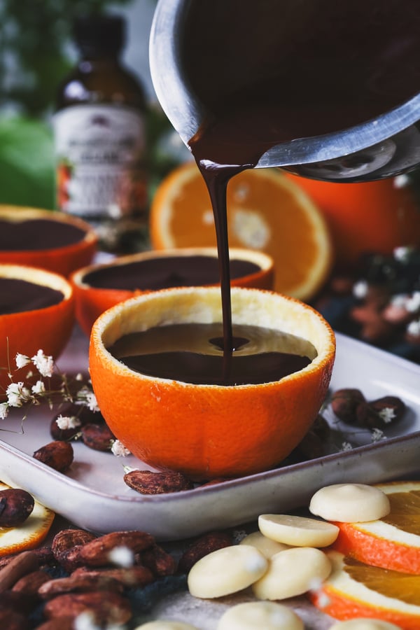 Melted chocolate being poured into hollowed out orange peel 
