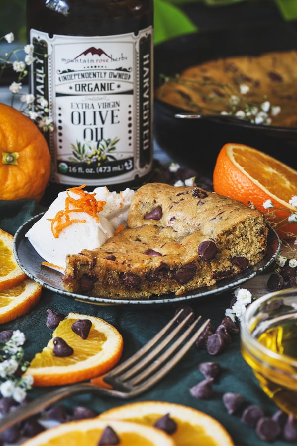A slice of orange chocolate cookie with vanilla ice cream and fresh oranges around it
