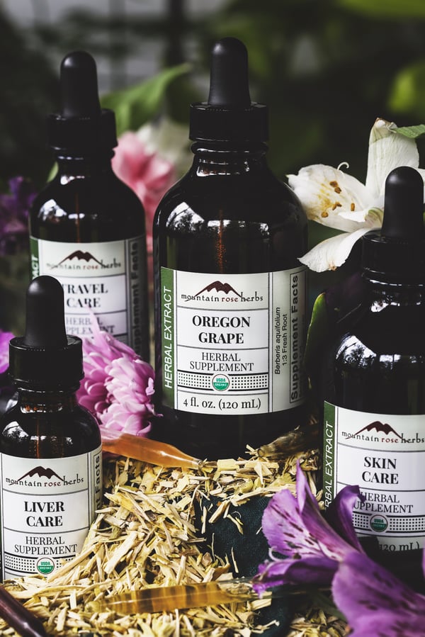 A selection of herbal extracts that contain oregon grape amongst flowers and dried oregon grape root