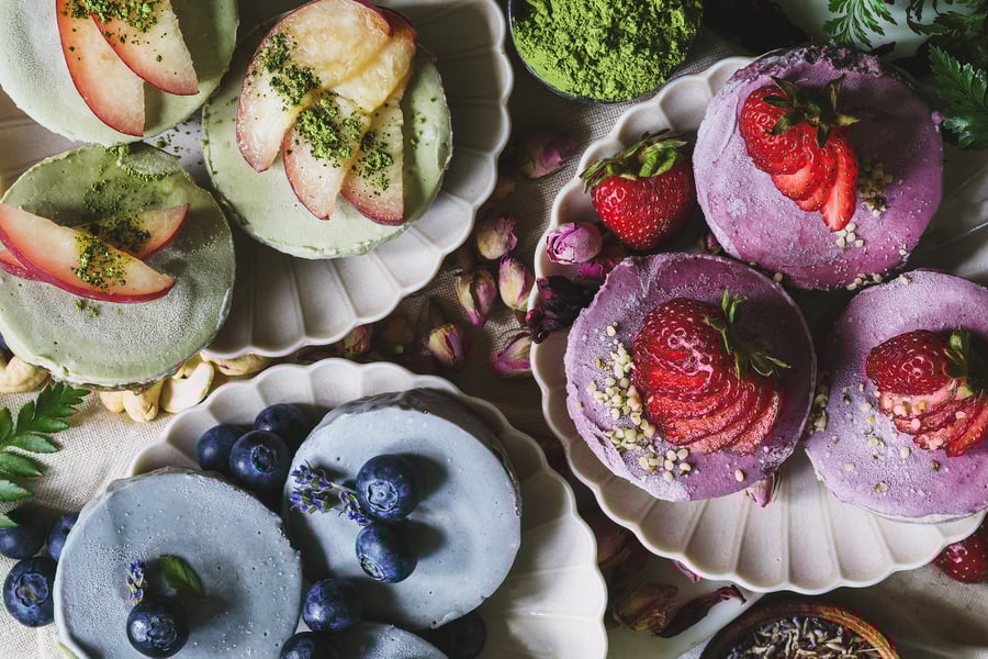 An overhead close up shot of the three different flavors of vegan cheesecakes with fruit on top