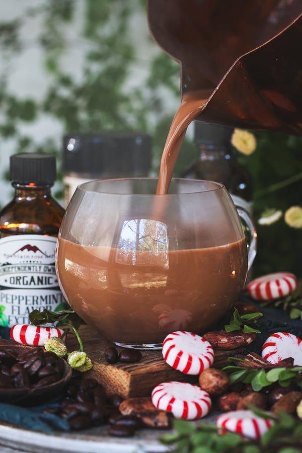 Steamy mocha being poured into small glass mug with ingredients nearby