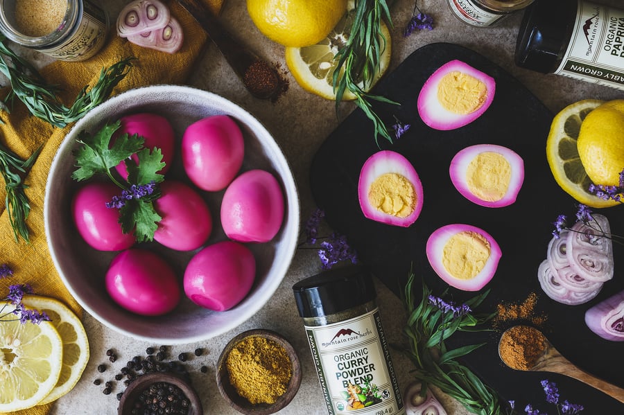 A bowl of peeled eggs with ingredients for making deviled eggs around it