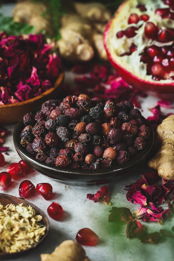 A small dish of hawthorn berries next to other ingredients for queen of hearts simple syrup