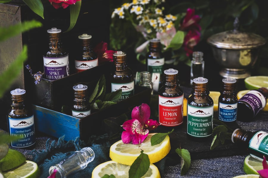 A selection of essential oils out on a work surface and empty bottles for blending