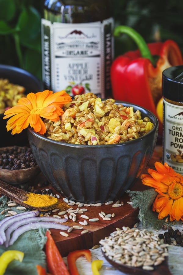 A close up photo of rye berry salad with ingredients around it