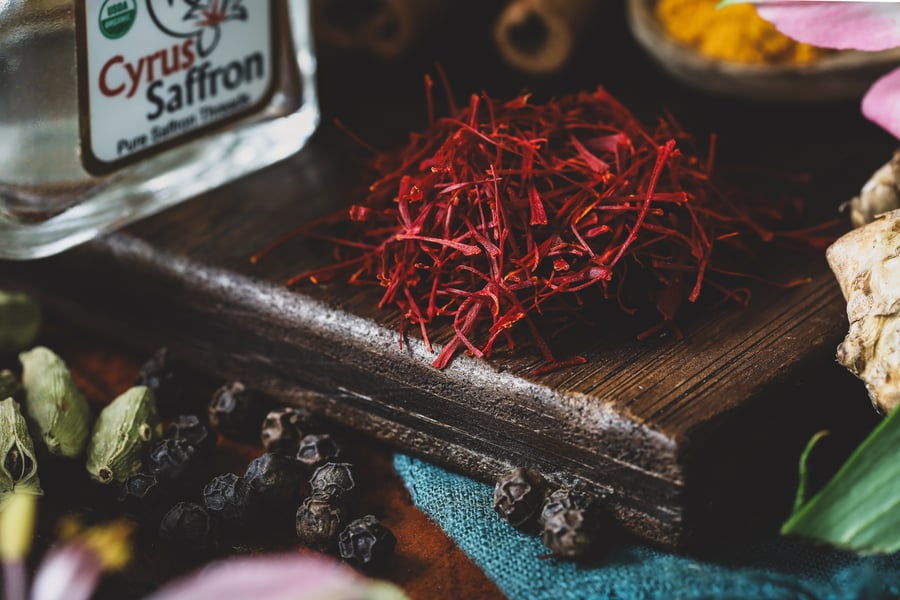 A pile of precious saffron threads sits out on a board with other spices nearby