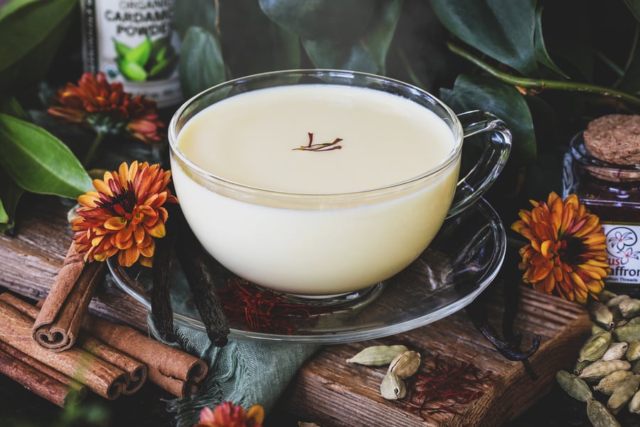 A warm saffron latte sits surrounded by ingredients