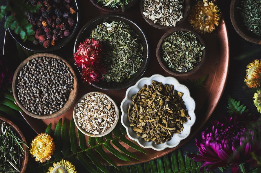 Overhead view of bowls of dried seasonal herbs on table top