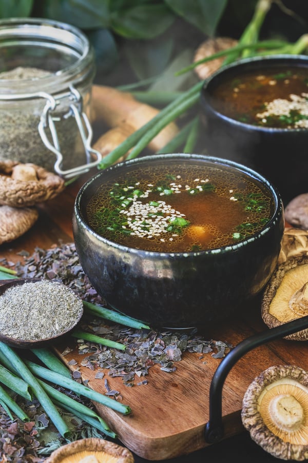 A bowl of vegan seaweed soup sits beside a spoonful of seaweed bouillon powder