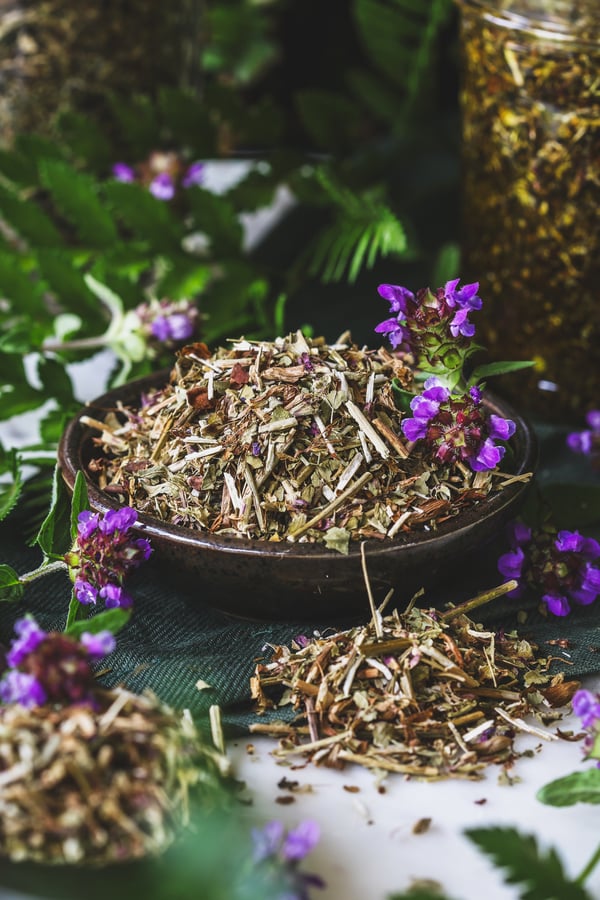 Dried self heal in a bowl surrounded by fresh flowers