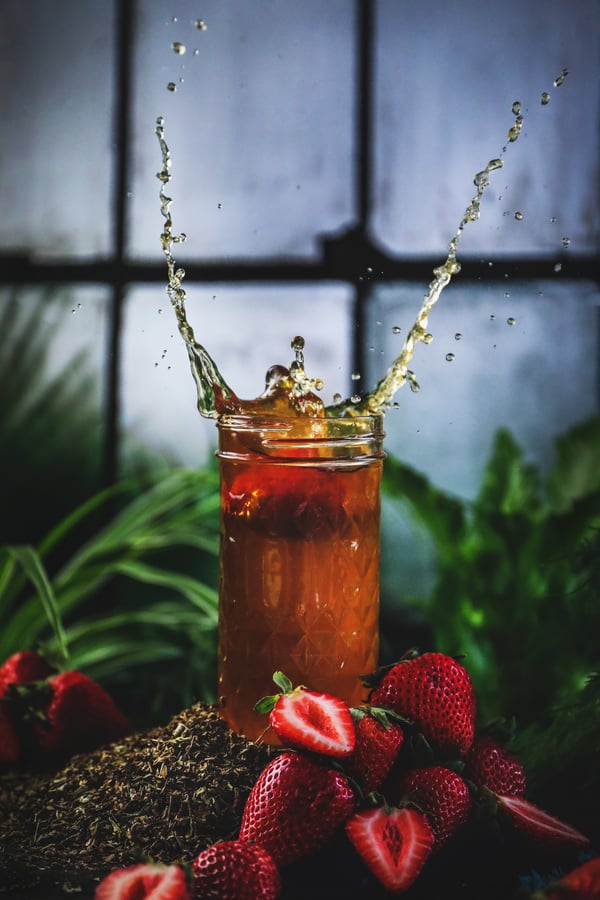 A strawberry and holy basil spritzer in a jar with berries and herbs.