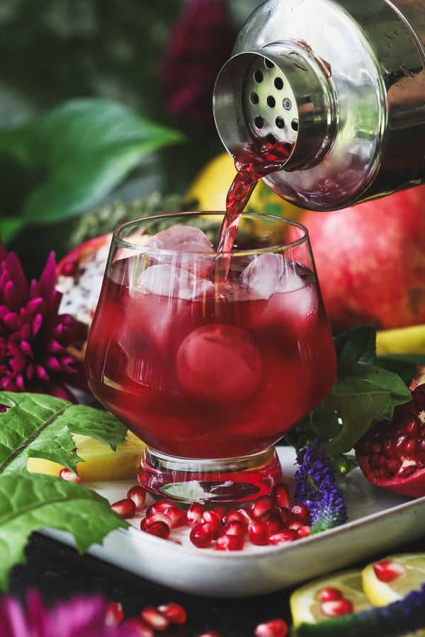 Mocktail being poured from shaker into a glass filled with ice