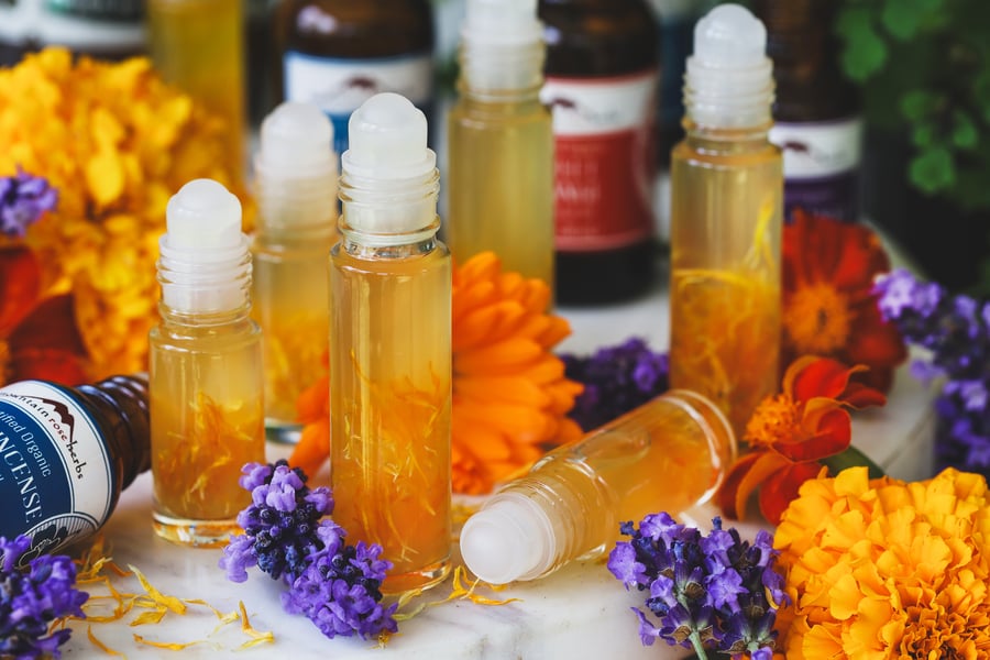Summer perfume in roll top bottles with fresh flowers around them