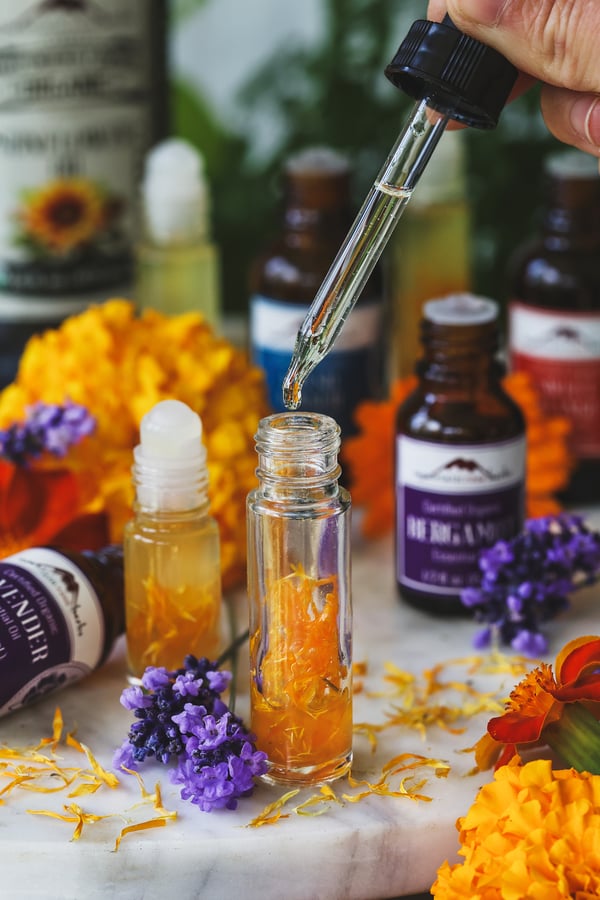 A dropper of sunflower oil gets dripped into a roll top bottle with essential oils in it
