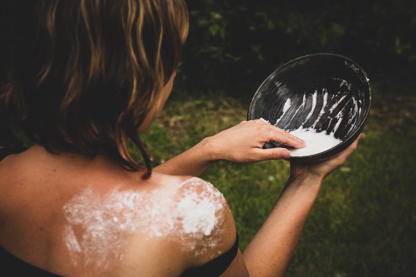 A person applying sun relief lavender paste to their back.