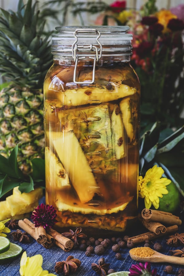 A jar of pineapple rind and spices sits ready to ferment into tepache