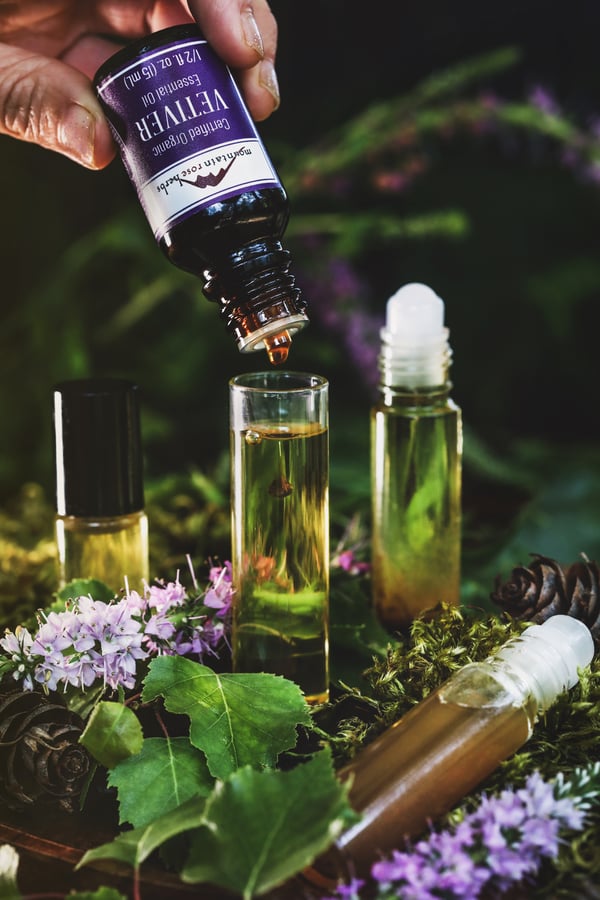 Vetiver essential oil being dripped into a bottle of carrier oil