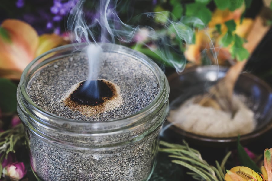 Waning moon incense smokes on a jar of sand