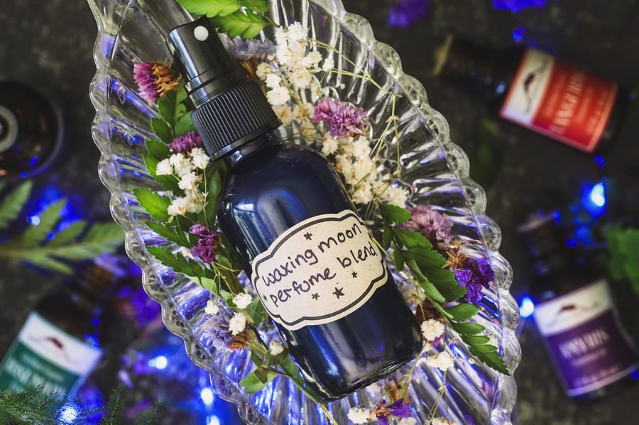A labeled bottle of perfume spray sits on a bed of flowers