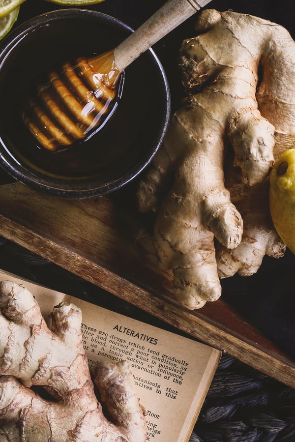 Fresh ginger root with lemon and honey nearby