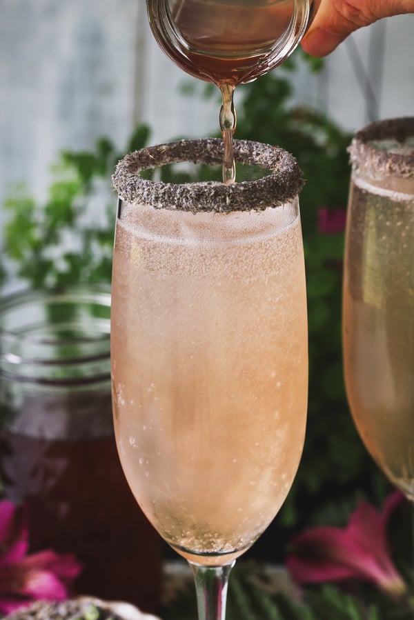 Oxymel being poured into a champagne flute of chilled tonic and club soda 