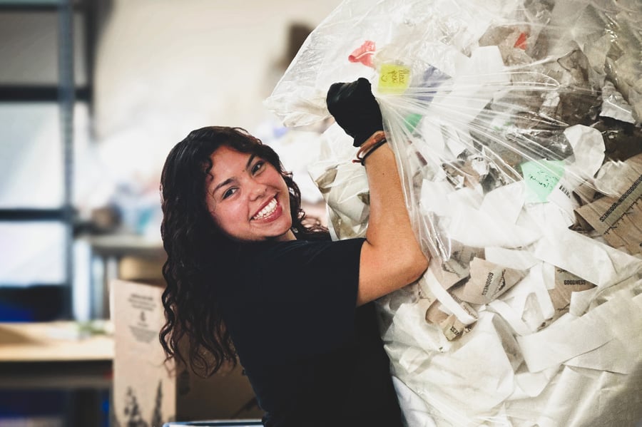 A facilities employee hauls a bag of recycling 