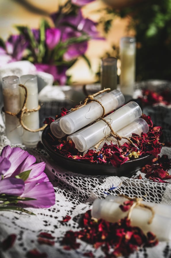 Photo of two lip balm tubes tied together with rustic twine- flowers in background. 