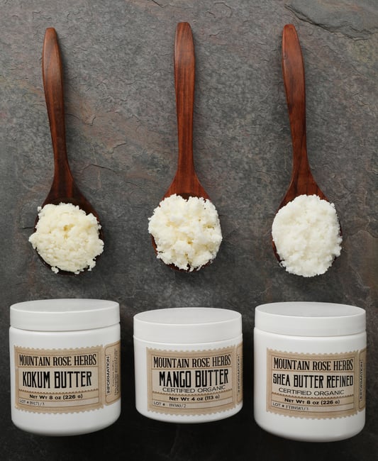 Three wooden spoons full of body butters. 