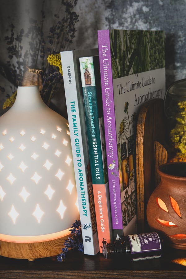 Aromatherapy books on a bookshelf with a diffuser. 