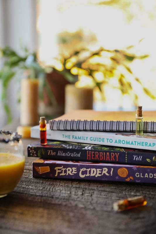Gifts for book lovers include new books like the Illustrated Herbiary, Fire Cider!, and The Family Guide To Aromatherapy. Arranged with essential oils and herbs.