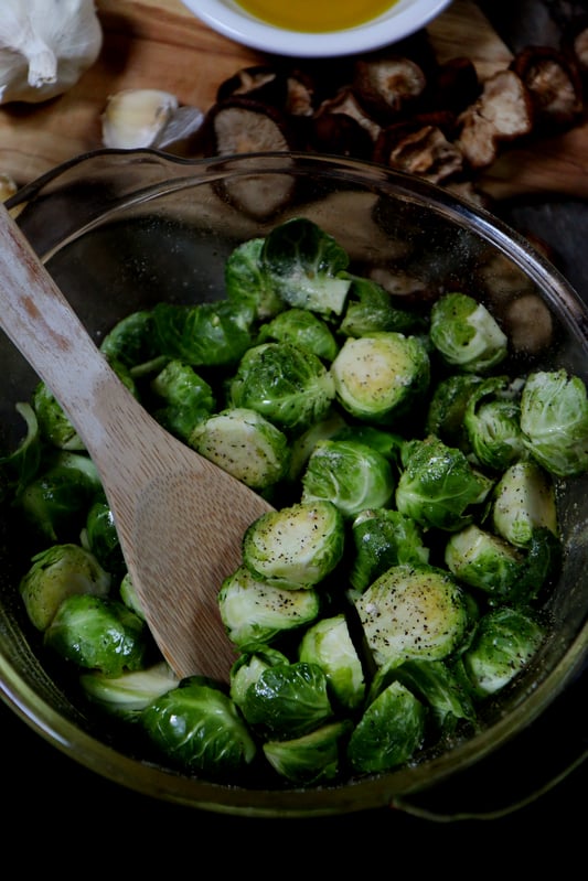 Seasoning brussels sprouts before roasting in garlic-infused olive oil. 