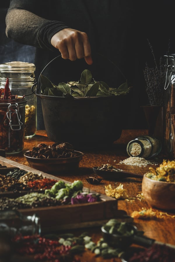 Colorful herbs displayed on table and in cast iron pot. 