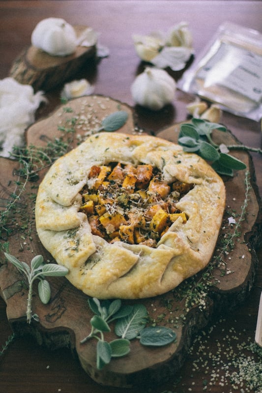 aerial view of savory squash galette on counter with dried and fresh herbs and spices