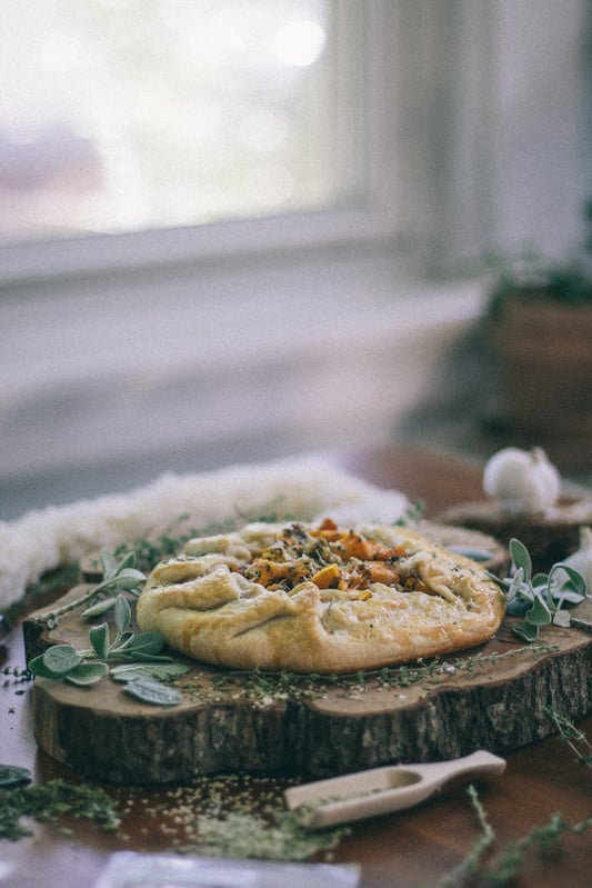 Butternut Squash Galette sitting on wooden tree stump latter on counter near window