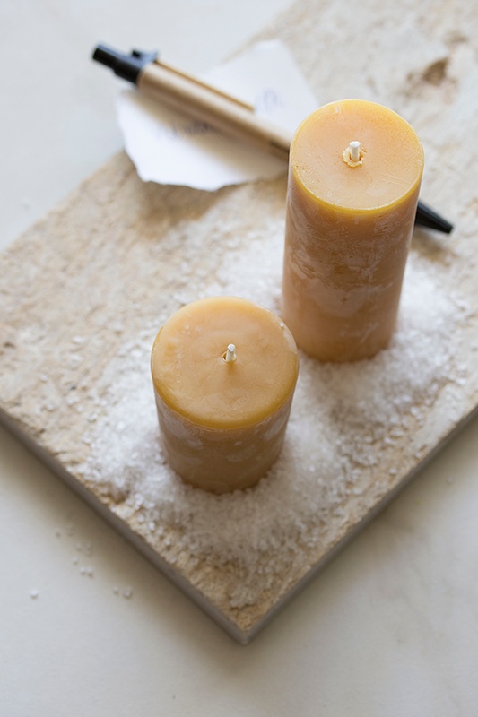 Beeswax candles with sprinkled sea salt on a wooden board