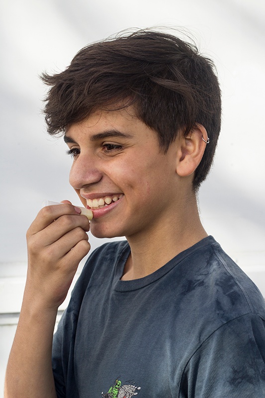 Young teenage boy applying lip balm and smiling