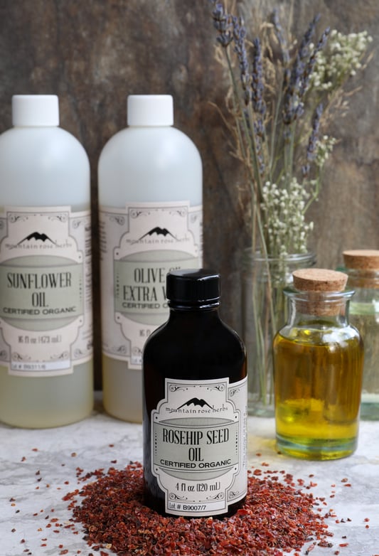 4 oz. bottle of rosehip seed oil on counter with rosehips and other carrier oils for use 4 oz. bottle of rosehip seed oil on counter with rosehips and other carrier oils for use