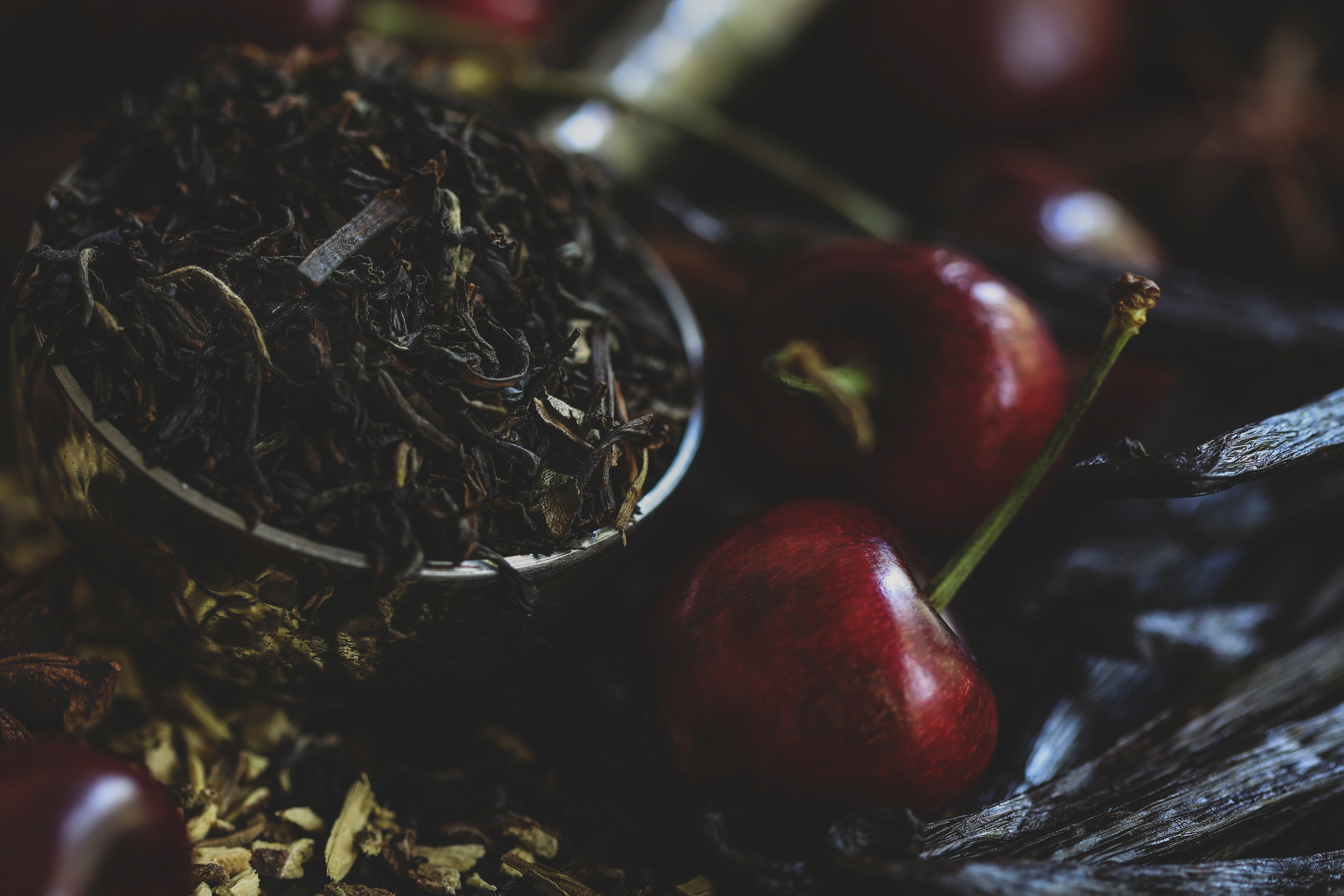 Fresh cherries surrounded by tea leaves and vanilla beans