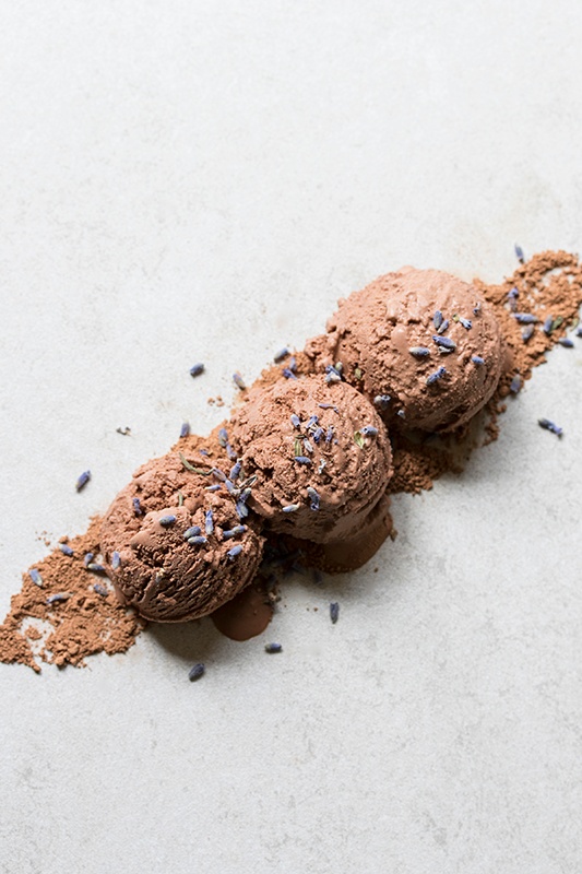 Three scoops of chocolate lavender ice cream sprinkled with lavender sitting on counter