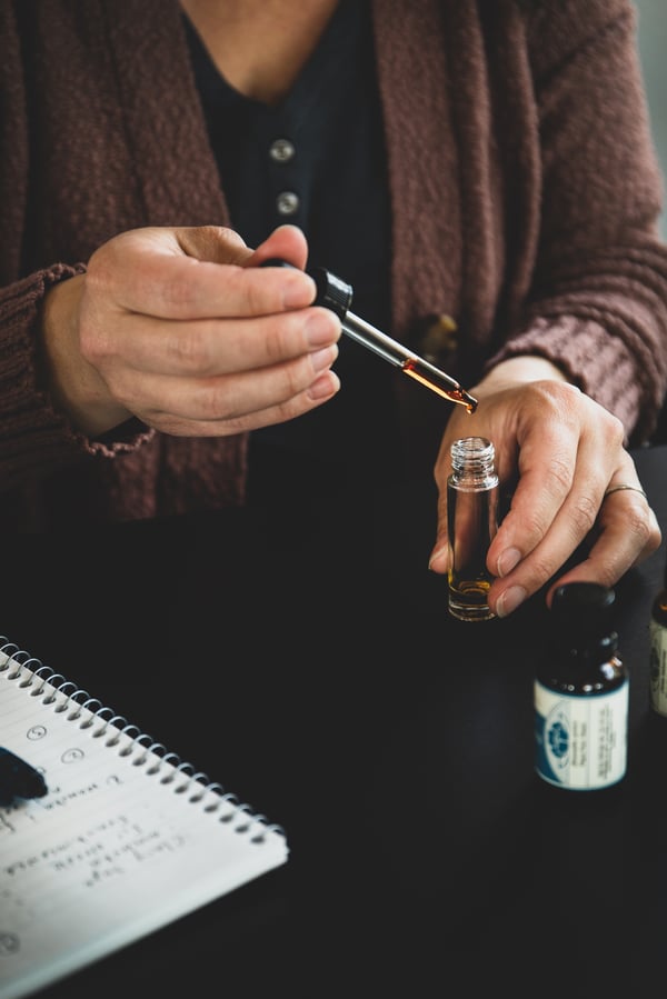 Hands dripping essential oils into a bottle.