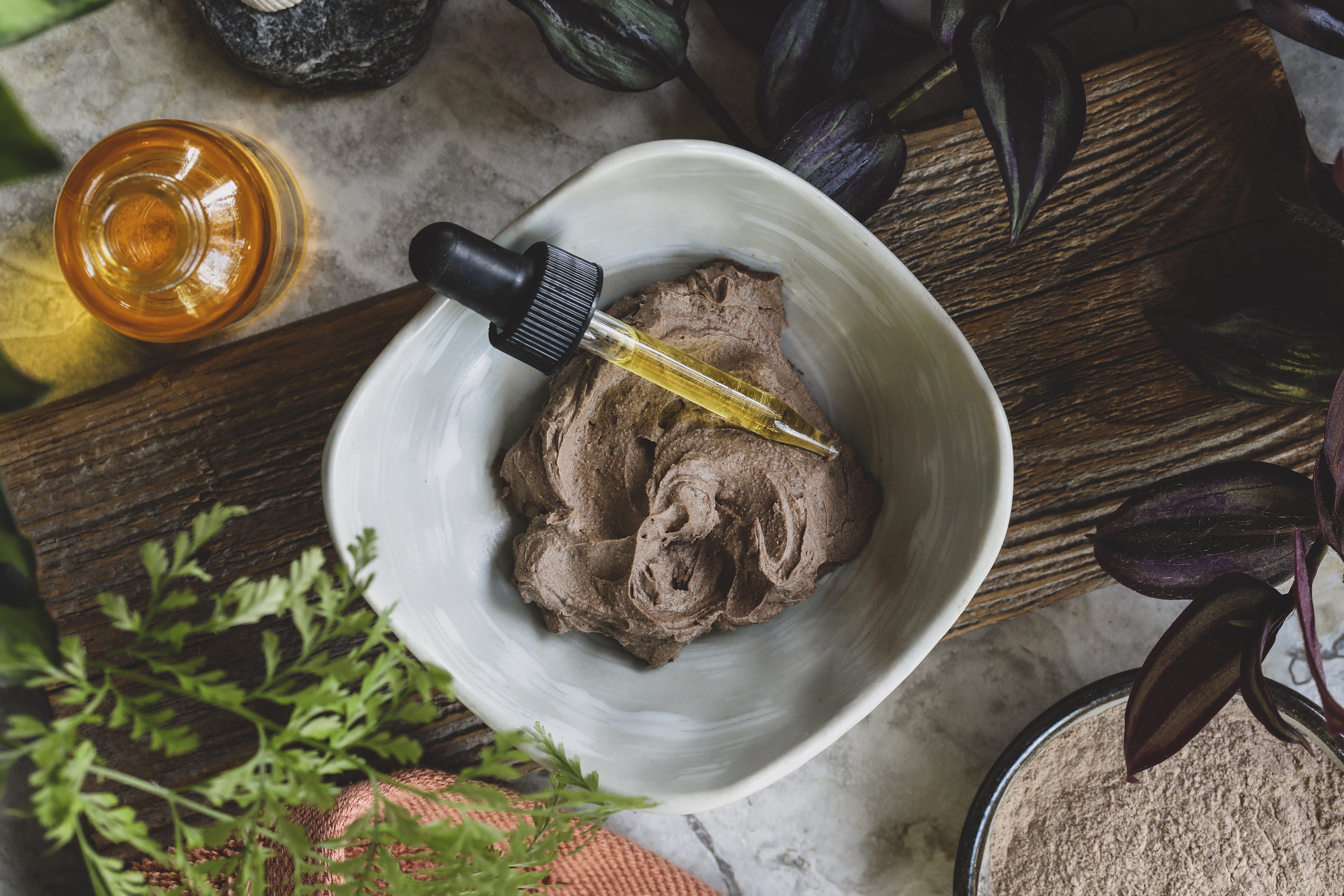 Clay Hair Mask in a white bowl surrounded by ingredients to make it. 