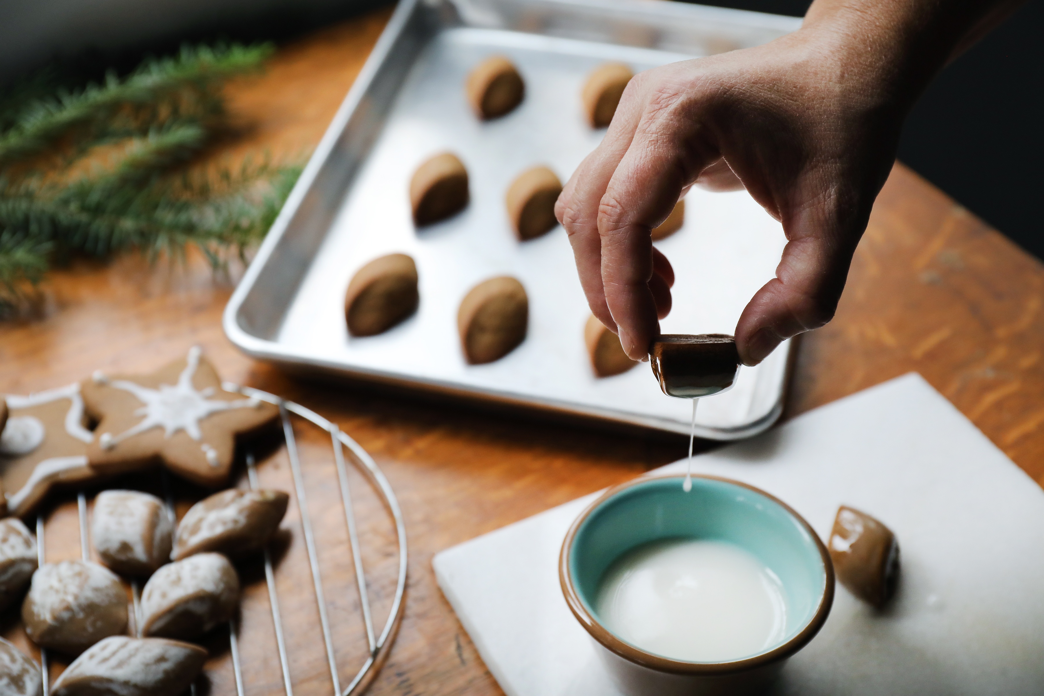 Hand dipping cookie in bowl of white glaze. 